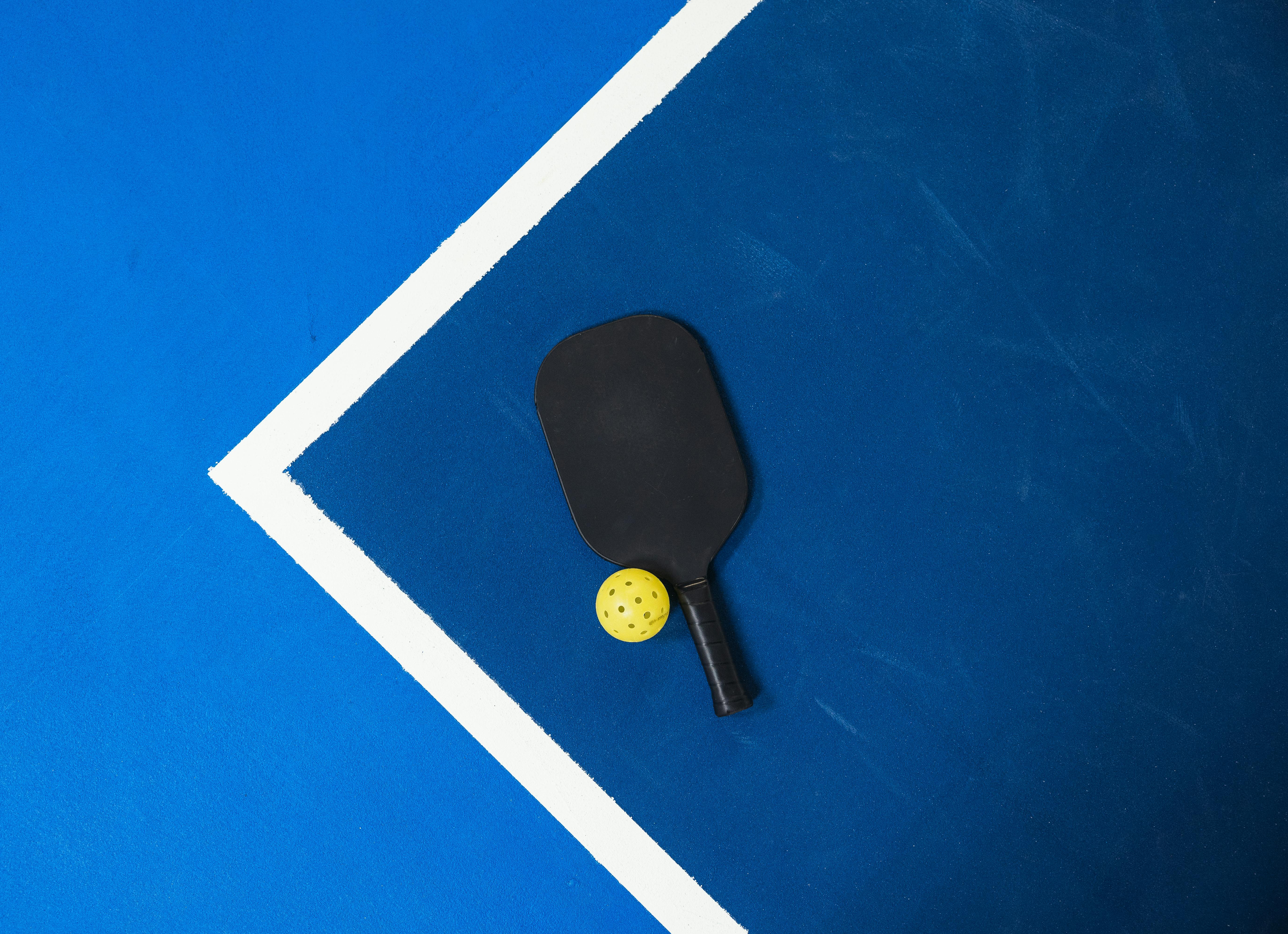 A pickleball paddle and ball on a blue court in Hong Kong